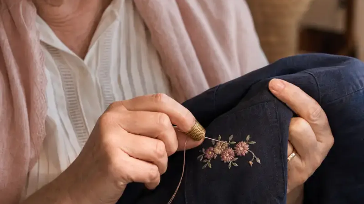 ’n Ouer vrou se hande stik ’n blommetjie op die sak van ’n baadjie.